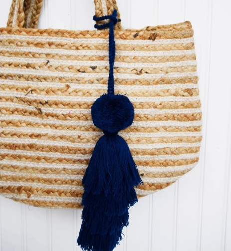 Small natural woven bag with a blue tassel hanging from the handle